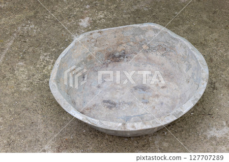Weathered dented gray aluminum basin on concrete floor 127707289