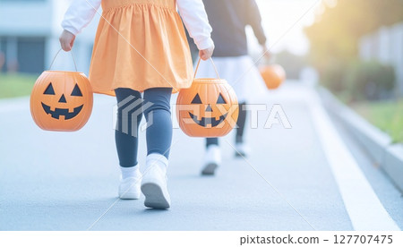 孩子們穿著萬聖節服裝,帶著南瓜籃在附近散步 孩子們穿著萬聖節服裝,帶著南瓜籃在附近散步 127707475