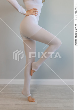 Woman in white suit for LPG massage. Anti-cellulite body care concept. Gray background Woman in white suit for LPG massage. Anti-cellulite body care concept. Gray background 127707499