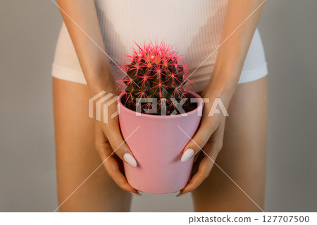 The concept of hair removal, smoothness. A woman with an orange cactus in her hands in underwear. The concept of hair removal, smoothness. A woman with an orange cactus in her hands in underwear. 127707500