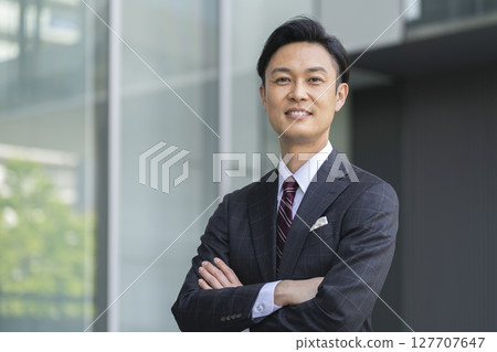 一位 40 多歲的商人微笑著，雙臂交叉，看著鏡頭 127707647