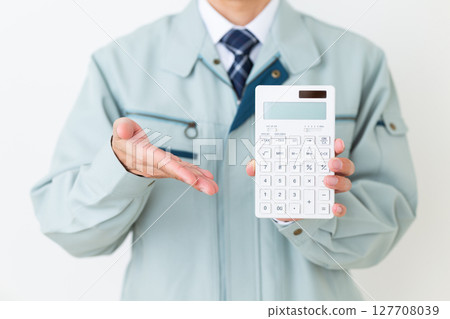 A middle-aged male businessman wearing green work clothes and holding a calculator 127708039