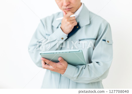 一位身穿綠色工作服、手持活頁夾和筆的中年男性商人 一位身穿綠色工作服、手持活頁夾和筆的中年男性商人 127708040