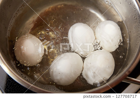 Chicken white eggs in boiling water in a metal saucepan. Boiled eggs 127708717