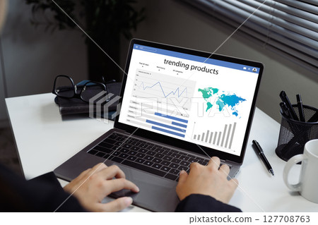 Person reviews charts and graphs showing trending product data, and global market insights Person reviews charts and graphs showing trending product data, and global market insights 127708763