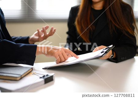 Close up of two business professionals discussing contract terms during a meeting Close up of two business professionals discussing contract terms during a meeting 127708811