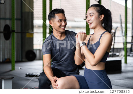 Fitness Coaching and Support. Personal trainer motivating a young woman during workout session. 127708825