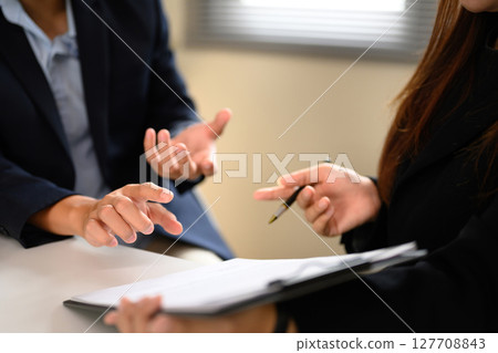 Business professionals in discussion over a contract document during a meeting 127708843