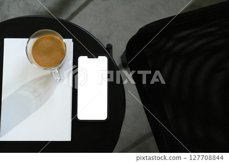 Top view of smartphone mockup with coffee and book on on a sleek black table Top view of smartphone mockup with coffee and book on on a sleek black table 127708844