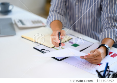 Man reviewing financial documents at modern office desk 127708892