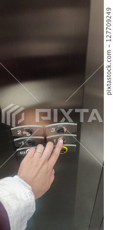 Finger Pressing Button in Modern Elevator Interior - Stainless Steel Lift Panel, Urban Movement, Accessibility, Transportation, and City Lifestyle 127709249