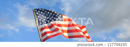 America flag wave under blue sky in celebration of the nation holiday for 4th of July, Memorial Day, Independence Day and celebrate victory with copy space on top with blue sky outdoor background America flag wave under blue sky in celebration of the nation holiday for 4th of July, Memorial Day, Independence Day and celebrate victory with copy space on top with blue sky outdoor background 127709285