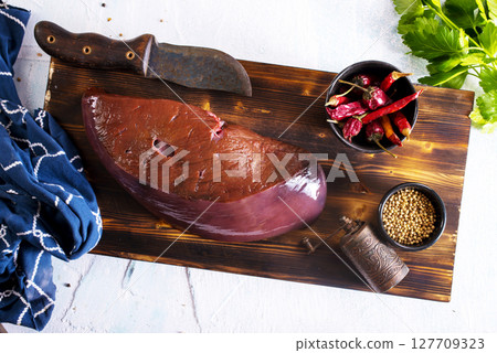 Raw Beef liver meat on wooden board with peppers 127709323