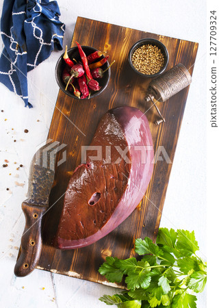 Raw Beef liver meat on wooden board with peppers Raw Beef liver meat on wooden board with peppers 127709324