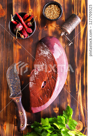 Raw Beef liver meat on wooden board with peppers 127709325
