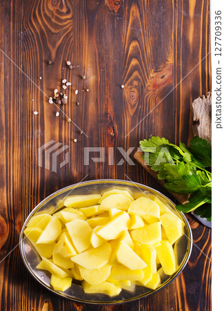 Spiced pieces of raw potato prepared to bake. Spiced pieces of raw potato prepared to bake. 127709336