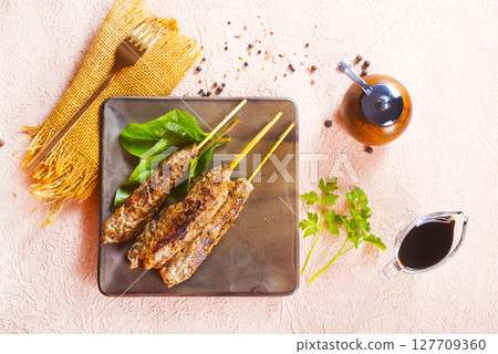 Grilled Lula kebab on skewers with spices in a claim plate on a table 127709360