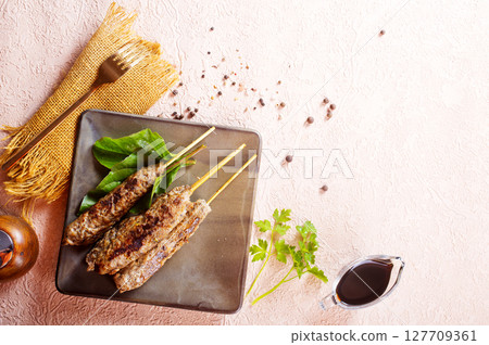 Grilled Lula kebab on skewers with spices in a claim plate on a table 127709361