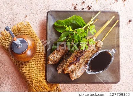 Grilled Lula kebab on skewers with spices in a claim plate on a table 127709363