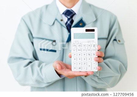A middle-aged male businessman wearing green work clothes and holding a calculator 127709456