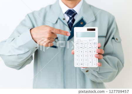 A middle-aged male businessman wearing green work clothes and holding a calculator A middle-aged male businessman wearing green work clothes and holding a calculator 127709457