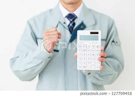 一位身穿綠色工作服、手持計算器的中年男性商人 一位身穿綠色工作服、手持計算器的中年男性商人 127709458