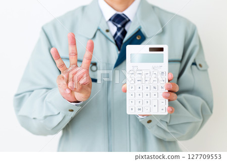 一位身穿綠色工作服的中年男性商人，手裡拿著計算器，三根手指向上指 127709553