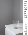 Minimalist glass of water on white bedside table. Health daily routine habits 127710771