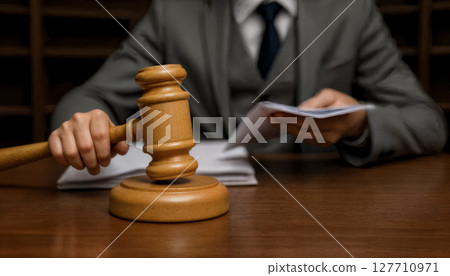 judge holds documents in one hand and a wooden gavel in the other 127710971