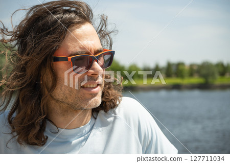 Happy caucasian brunette man in sunglasses wearing casual blue t-shirt sunglasses stand at urban park. Summer. Background for reflection. Happy caucasian brunette man in sunglasses wearing casual blue t-shirt sunglasses stand at urban park. Summer. Background for reflection. 127711034