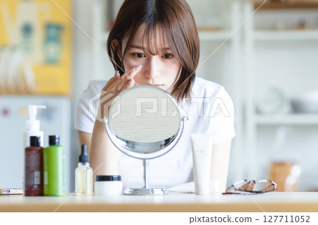 女人對著鏡子檢查自己的皮膚 127711052