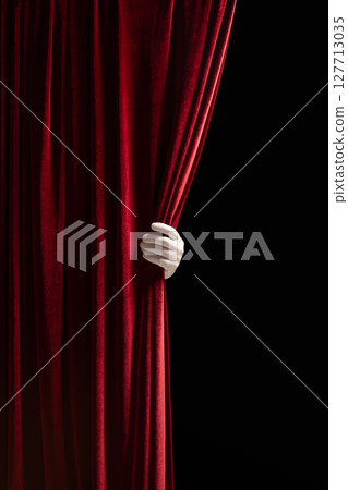 Red velvet curtain pulled aside by hand, revealing black emptiness. Theater posters, film teasers. 127713035