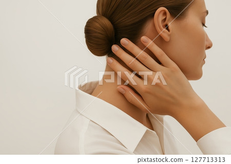 Woman in white shirt holding her neck in side view. Concept of neck pain, muscle tension, physical discomfort, stress-related strain, cervical spine issues, copy space, white background 127713313