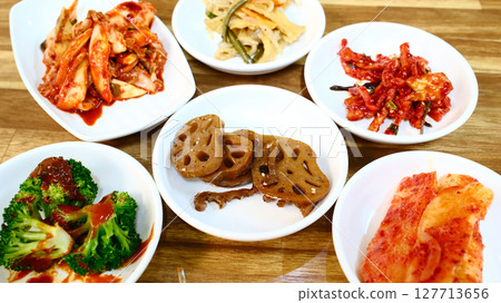 Traditional Korean banchan feast with multiple fermented vegetable side dishes including kimchi lotus root and pickled vegetables spread 127713656