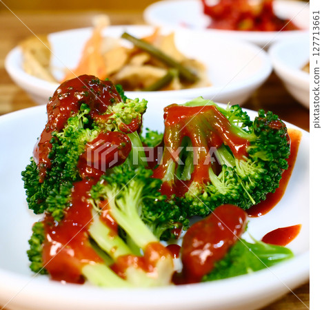 Fresh broccoli with savory brown sauce Korean side dish banchan served on white plate as part of traditional Korean meal 127713661