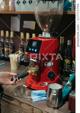Female barista using modern coffee machine in cafeteria 127713768