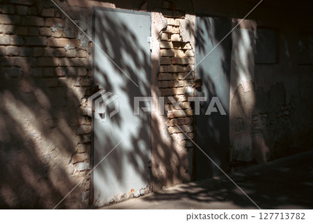 The photograph captures the interplay of light and shadow on an aged brick wall, creating a textured 127713782
