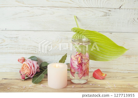 Spa still life with pink fresh roses flowers, candle and rose petal water, on wooden background. Alternative medicine, aromatherapy, body care. Spa still life with pink fresh roses flowers, candle and rose petal water, on wooden background. Alternative medicine, aromatherapy, body care. 127713955