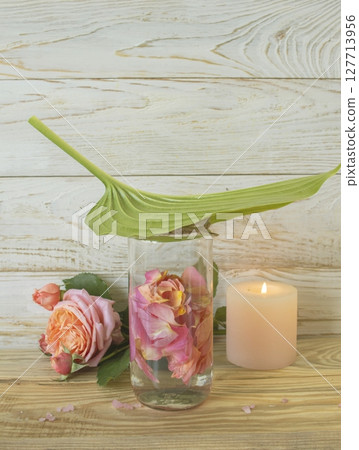 Spa still life with pink fresh roses flowers, candle and rose petal water, on wooden background. Alternative medicine, aromatherapy, body care. Spa still life with pink fresh roses flowers, candle and rose petal water, on wooden background. Alternative medicine, aromatherapy, body care. 127713956