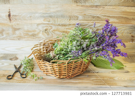 Medicinal herbs in a wicker basket on a wooden background, alternative medicine, natural raw materials. 127713981