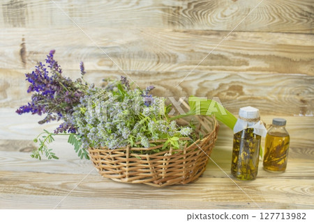 Medicinal herbs in a wicker basket on a wooden background, alternative medicine, natural raw materials. 127713982