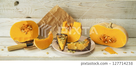 Slices of pumpkin pie with pumpkin seeds and pumpkin on wooden background. Slices of pumpkin pie with pumpkin seeds and pumpkin on wooden background. 127714238