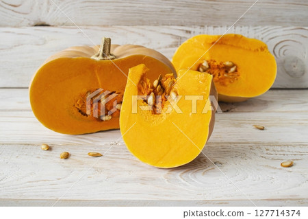 Pumpkin slices with seeds on white wooden background. Healthy, seasonal, vegetarian food. 127714374