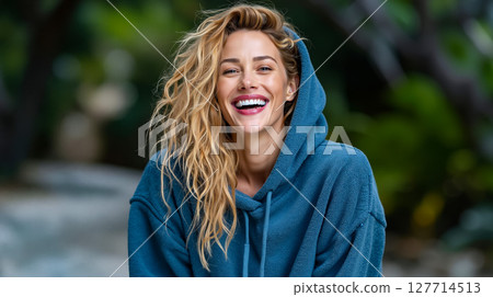 A woman in a blue hoodie smiles at the camera 127714513