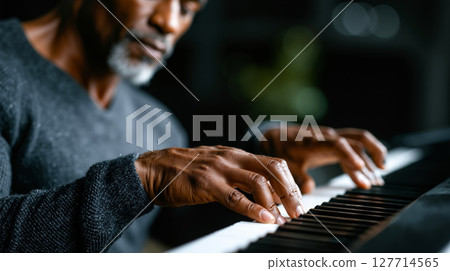 A man playing a piano with his hands on the keys 127714565