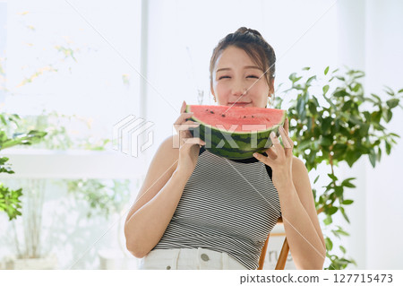 年輕女子在房間裡吃西瓜的夏季生活方式 127715473