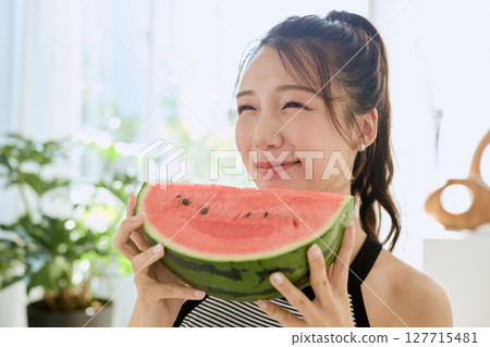 年輕女子在房間裡吃西瓜的夏季生活方式 年輕女子在房間裡吃西瓜的夏季生活方式 127715481