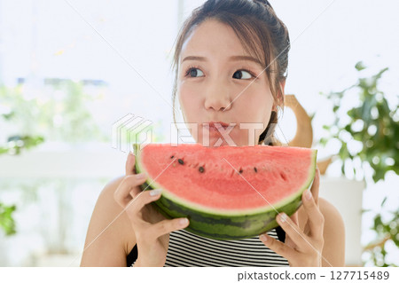 年輕女子在房間裡吃西瓜的夏季生活方式 年輕女子在房間裡吃西瓜的夏季生活方式 127715489