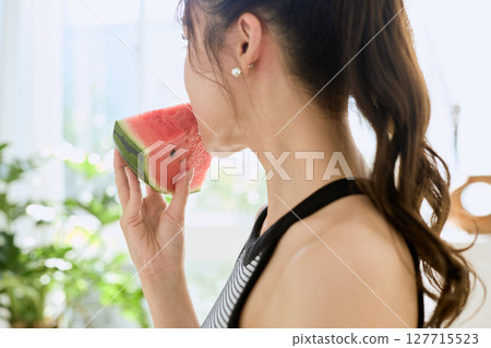 年輕女子在房間裡吃西瓜的夏季生活方式 年輕女子在房間裡吃西瓜的夏季生活方式 127715523