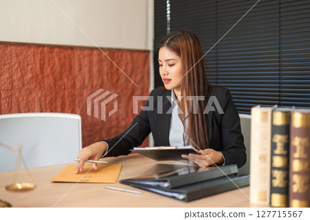 Lawyer and Legal Documents. A dedicated female lawyer reviewing important legal documents at her office desk. Lawyer and Legal Documents. A dedicated female lawyer reviewing important legal documents at her office desk. 127715567